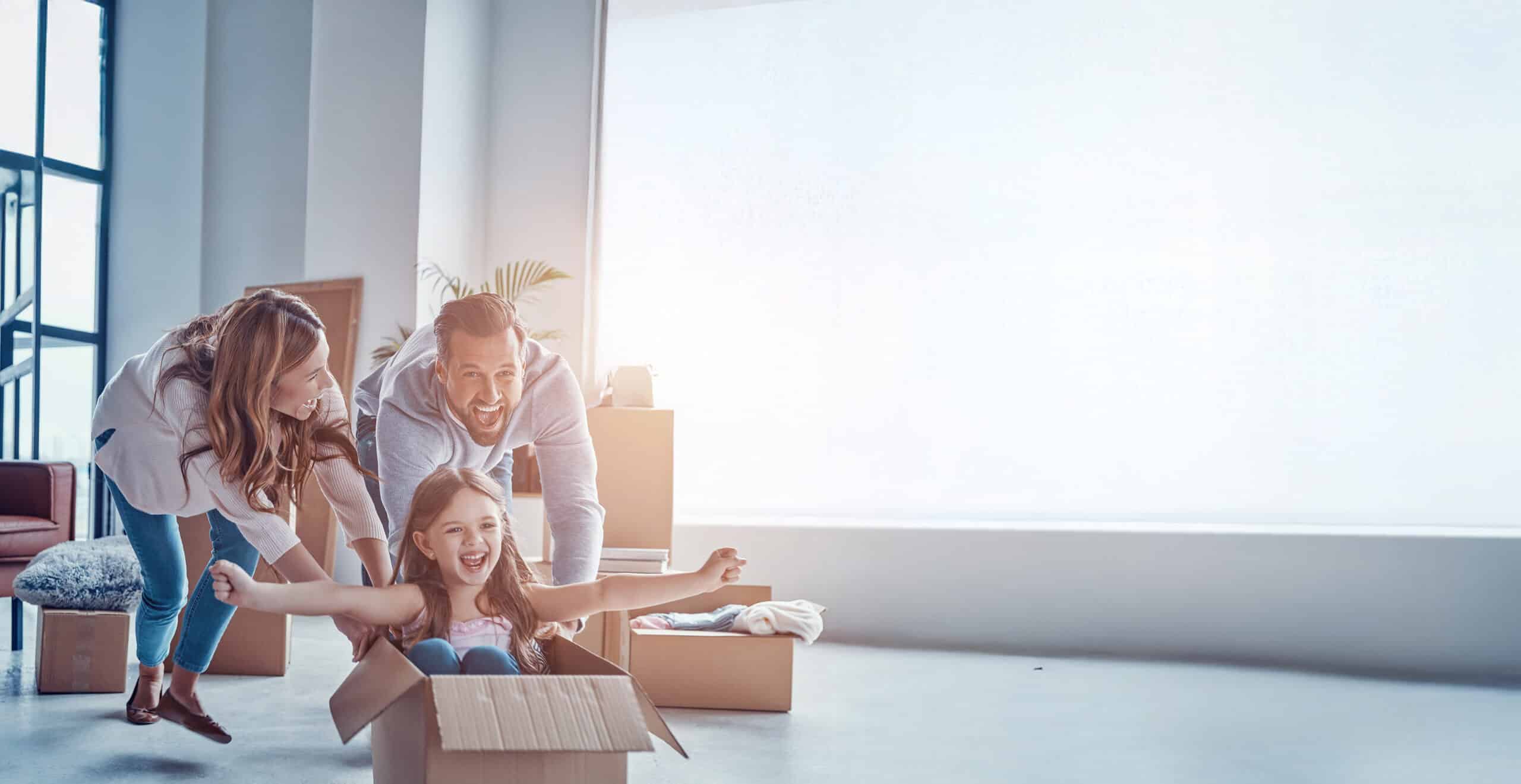Cheerful young family smiling and unboxing their stuff while moving into a new apartment