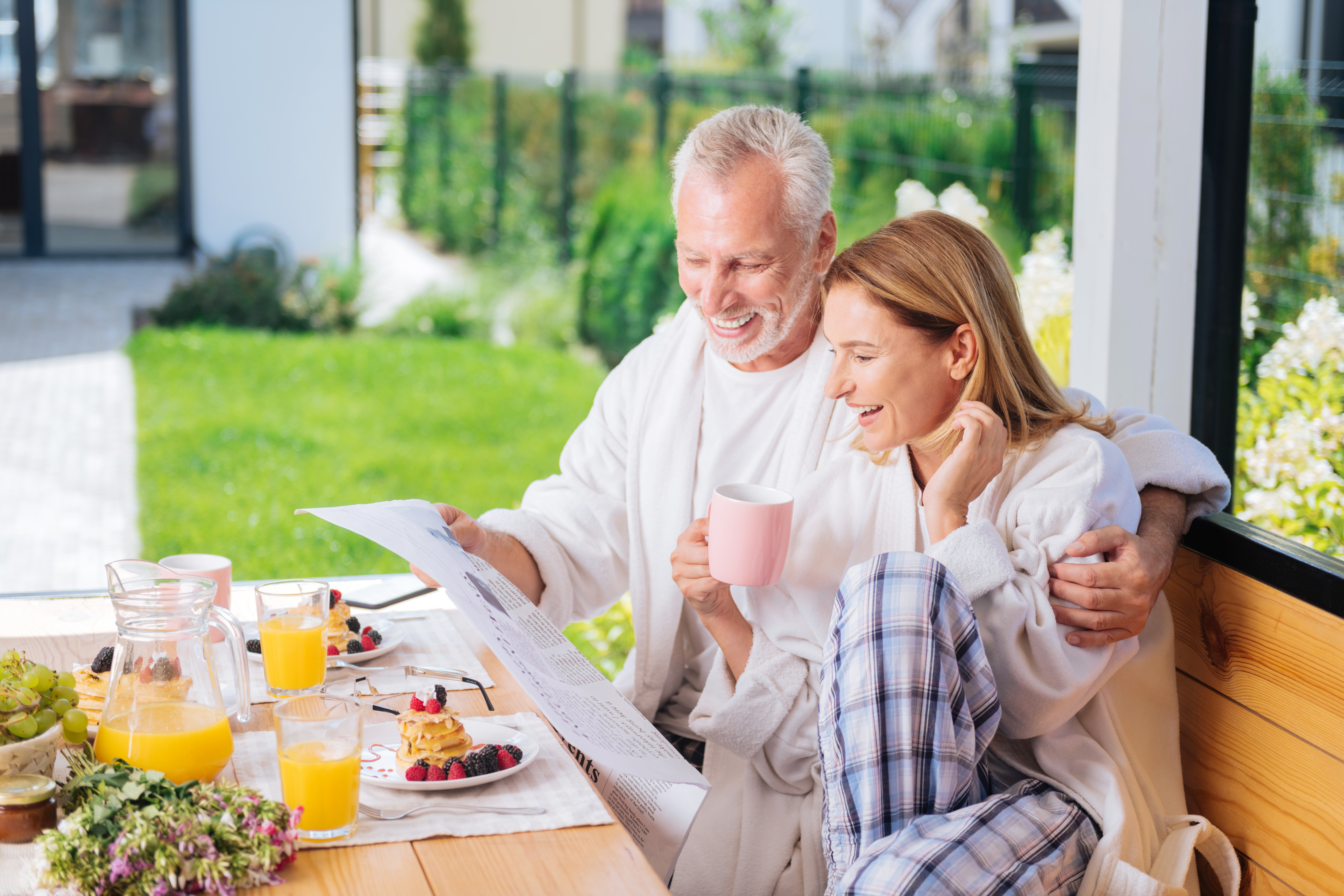 Beaming couple reading news after eating breakfast and drinking orange juice HZ Abos - Heidenheim an der Brenz